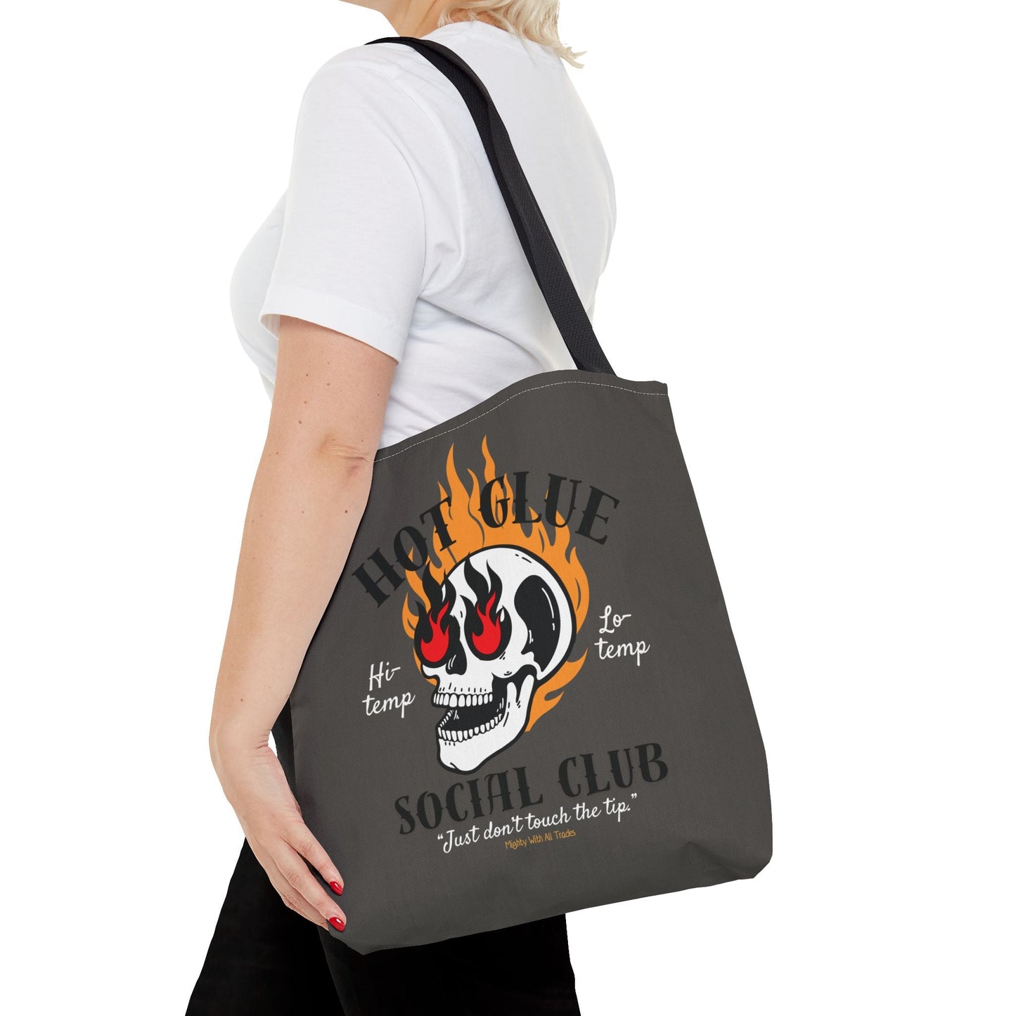 Person holding a gray tote bag with a skull design and text.