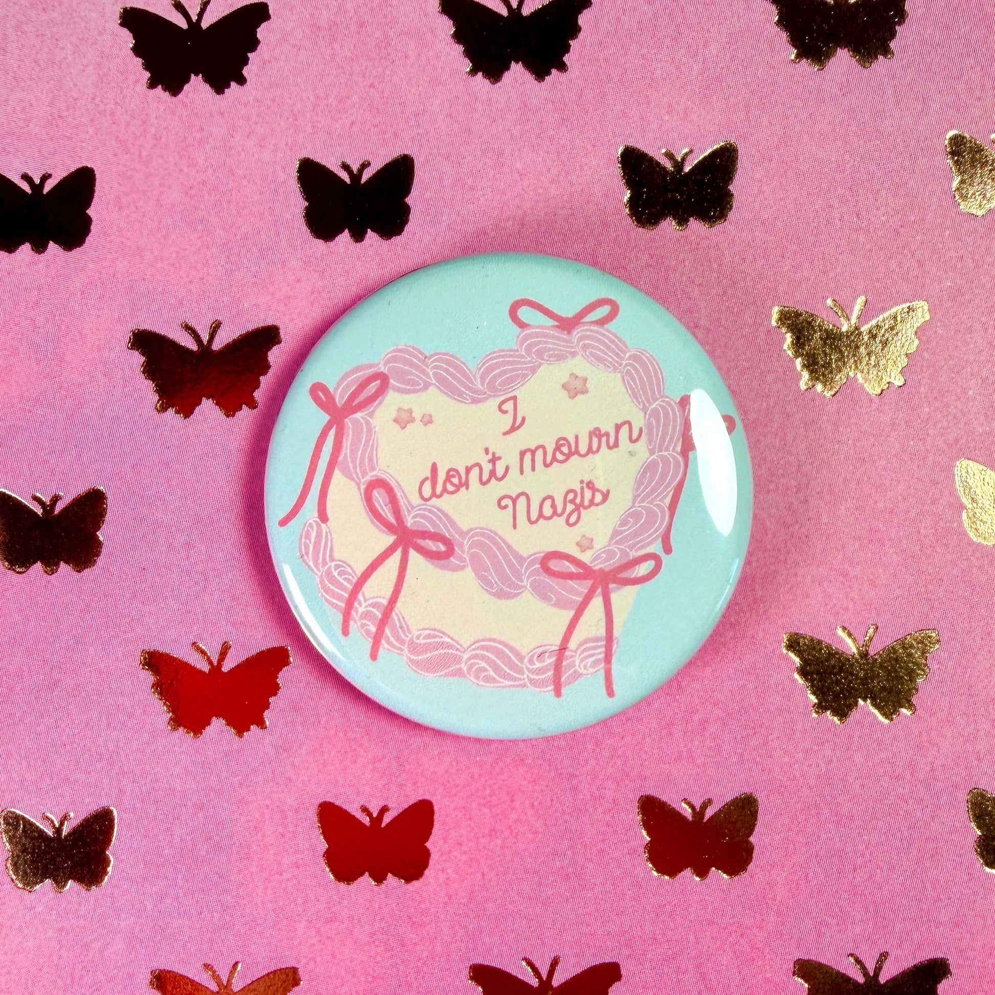 Button badge with 'I don't mourn nazis' text on a pink background with butterflies
