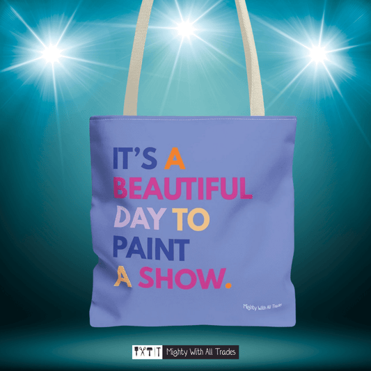 Purple tote bag with it's a beautiful day to paint a show colorful text on a blue background