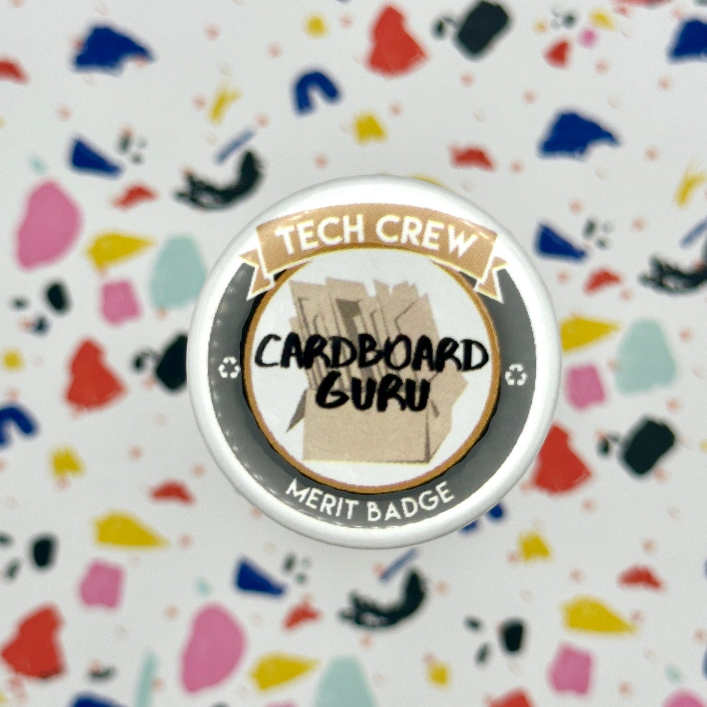 Merit badge with 'Tech Crew Cardboard Guru' text on a colorful, textured background