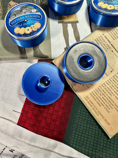 Blue pattern weights with a lid on a surface with printed material underneath