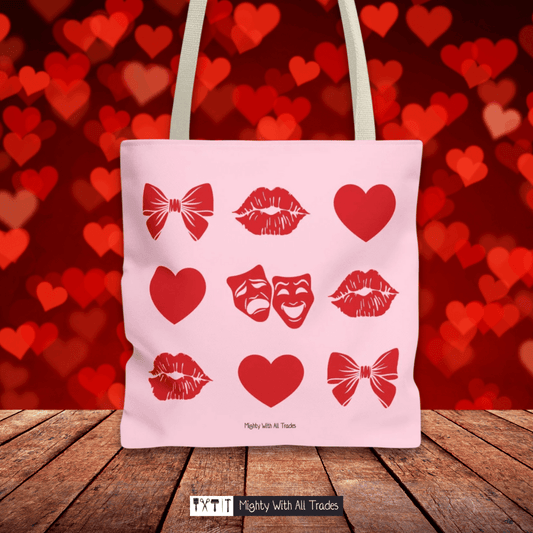 Pink tote bag with red theatre themed graphics on a wooden surface and heart-patterned background