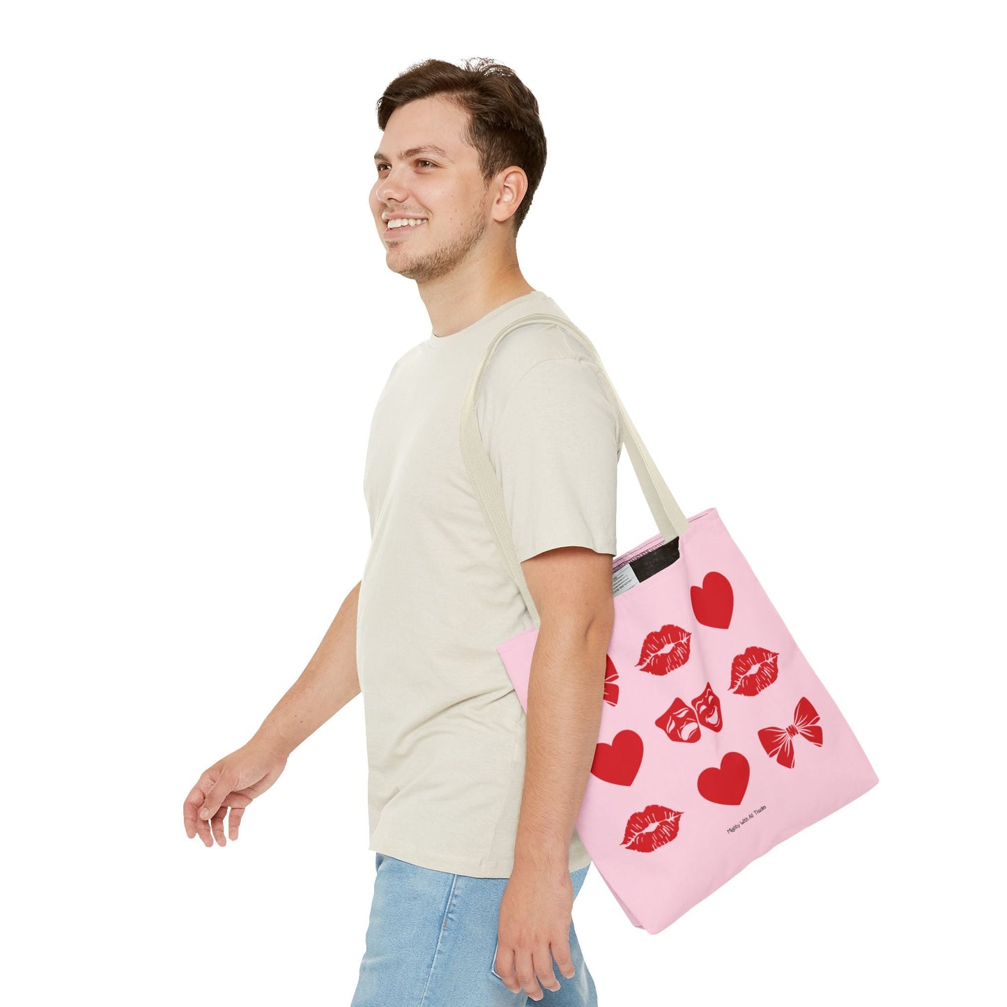 Man holding a pink tote bag with red heart and bow designs on a white background