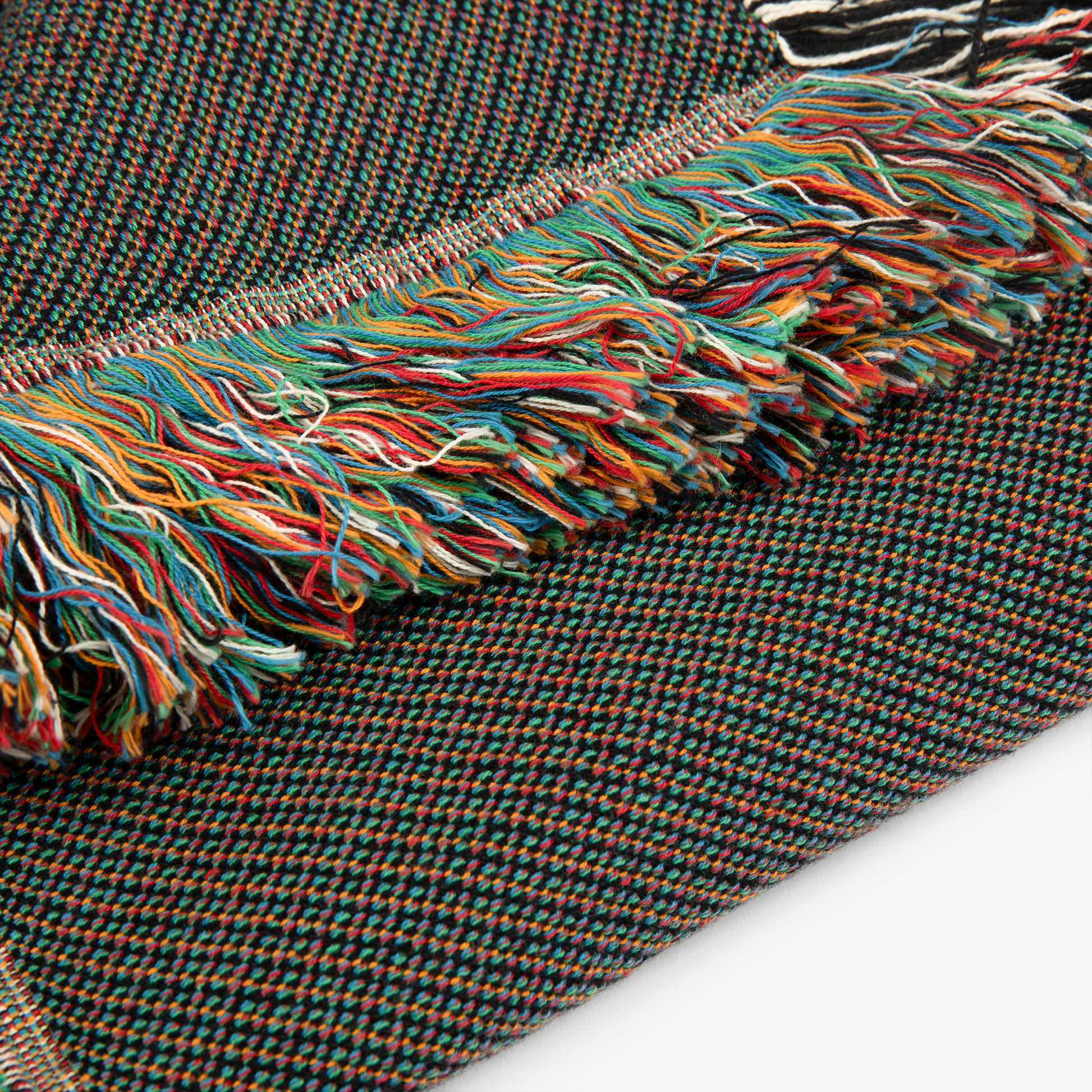 Close-up of a woven fabric with colorful fringe on a white background