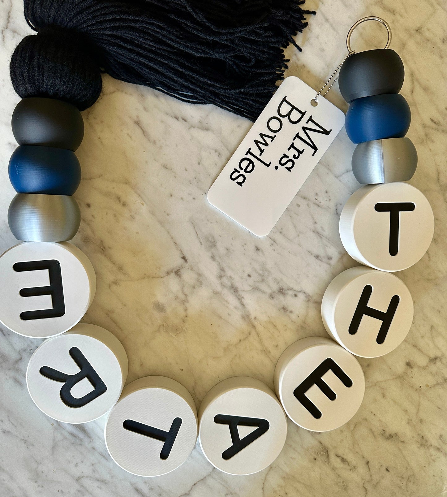 Bracelet with letter beads spelling 'THEATRE' on a marble surface