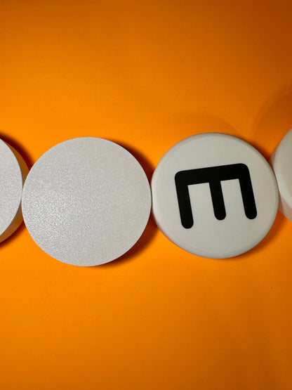 Round white beads with black symbols on an orange background