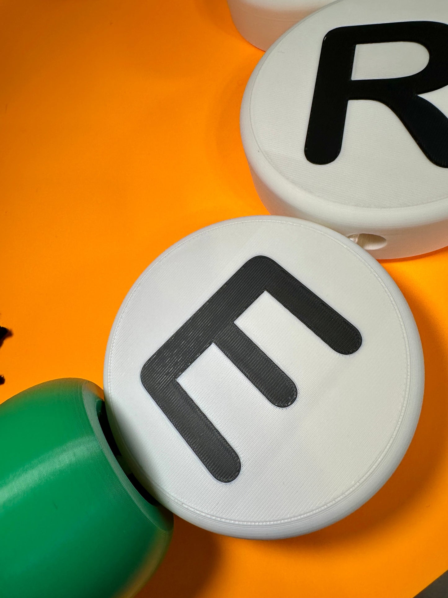 Two round white beads with black letters 'R' and 'E' on an orange background