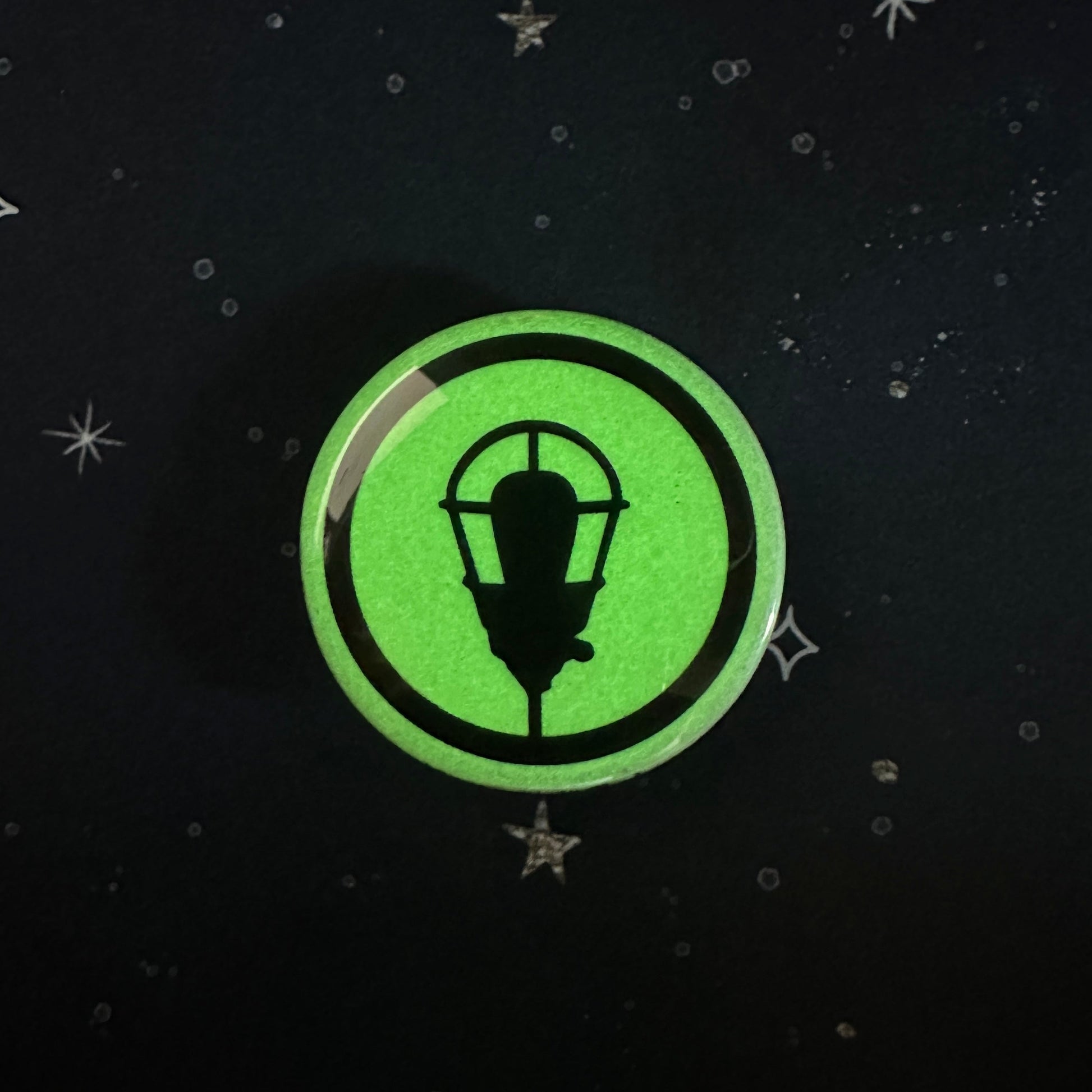 Green circular glow-in-the-dark sticker with a black lamp design on a dark background.