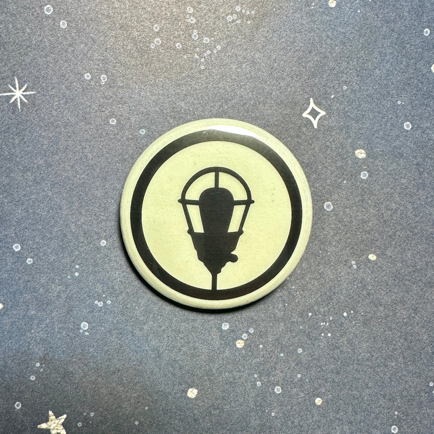 Glowing button with a black lamp design on a textured gray background with star shapes.