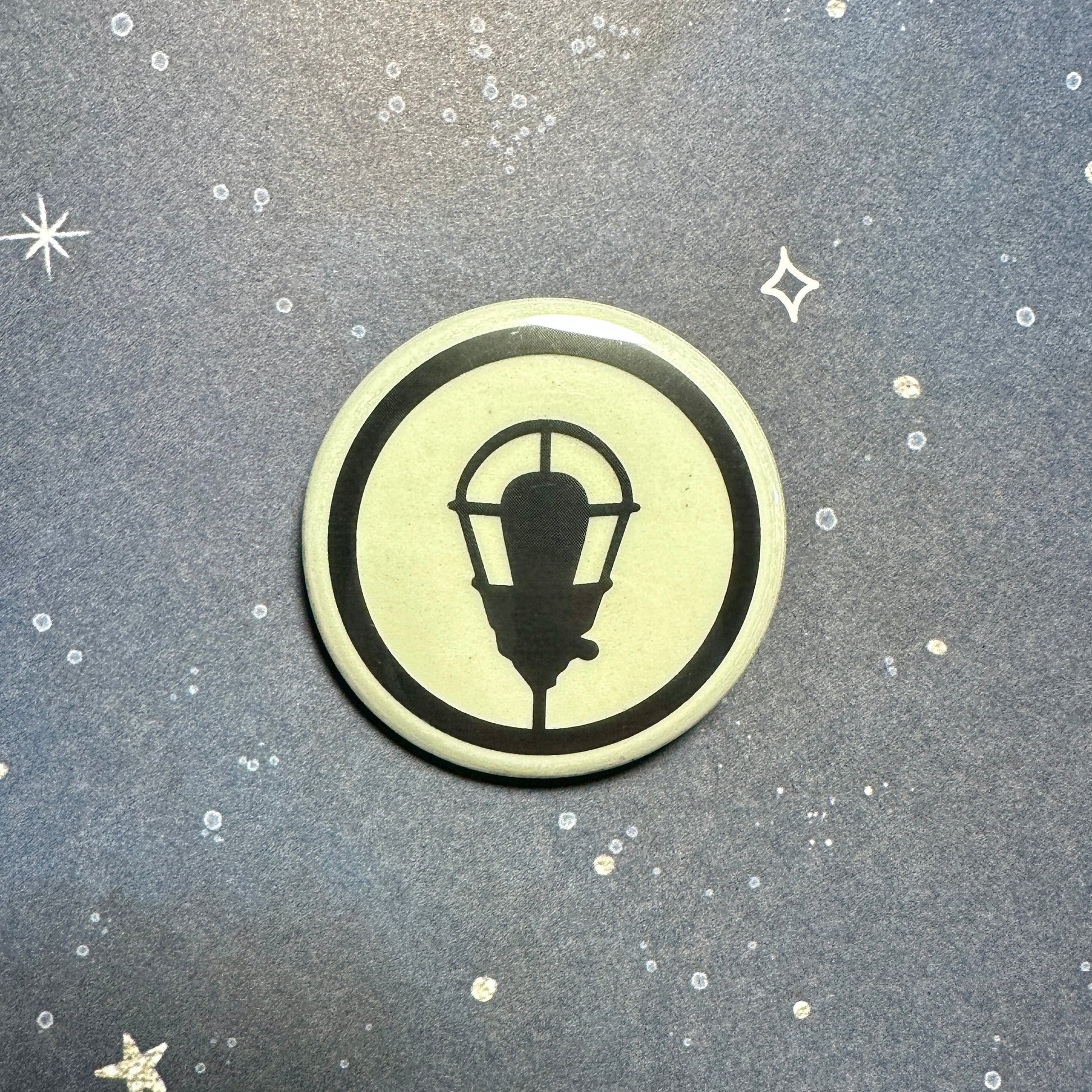 Glowing button with a black lamp design on a textured gray background with star shapes.