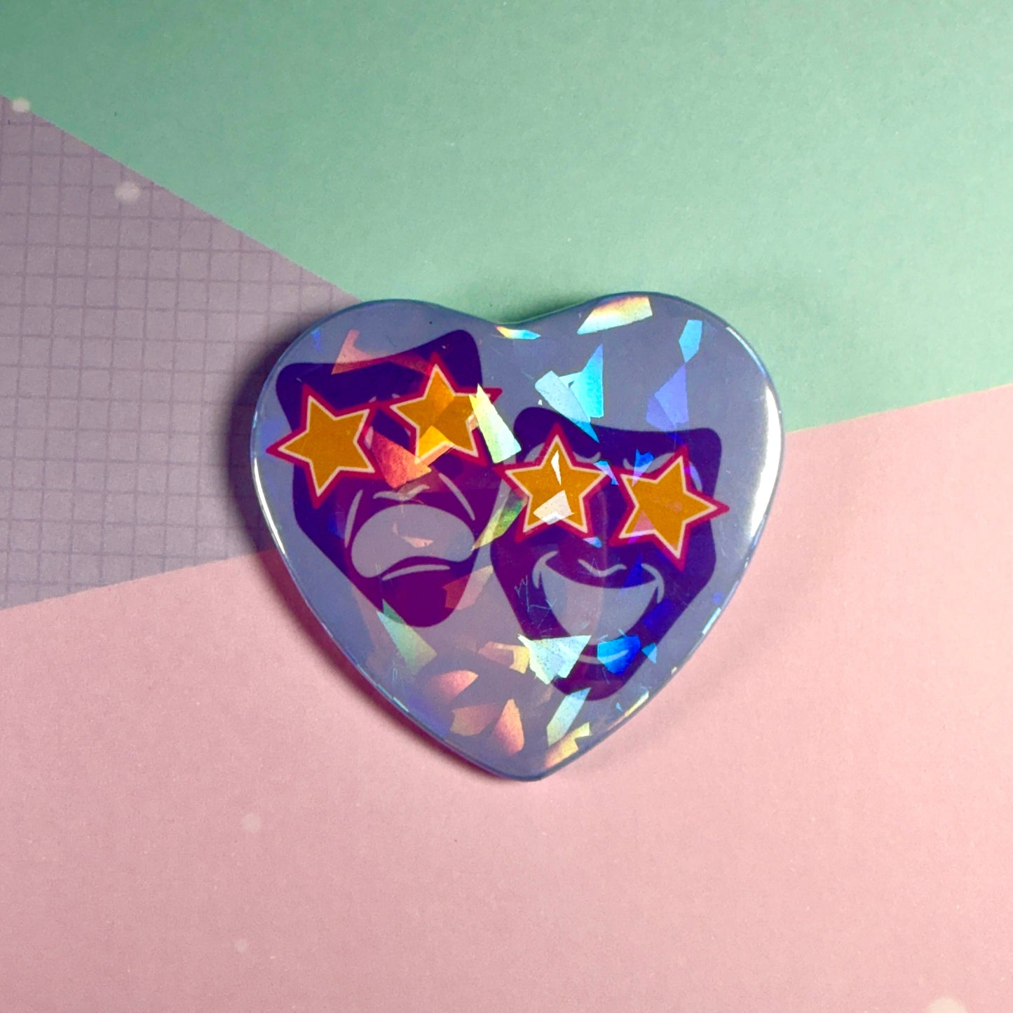 Holographic heart-shaped pin with star and face design on a pink and green background