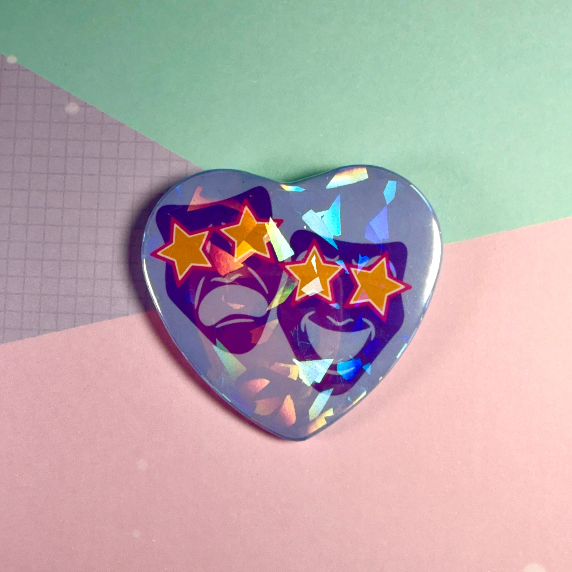 Holographic heart-shaped pin with star and face design on a pink and green background